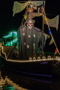 A spooky skeleton figure on a decorated boat at night.