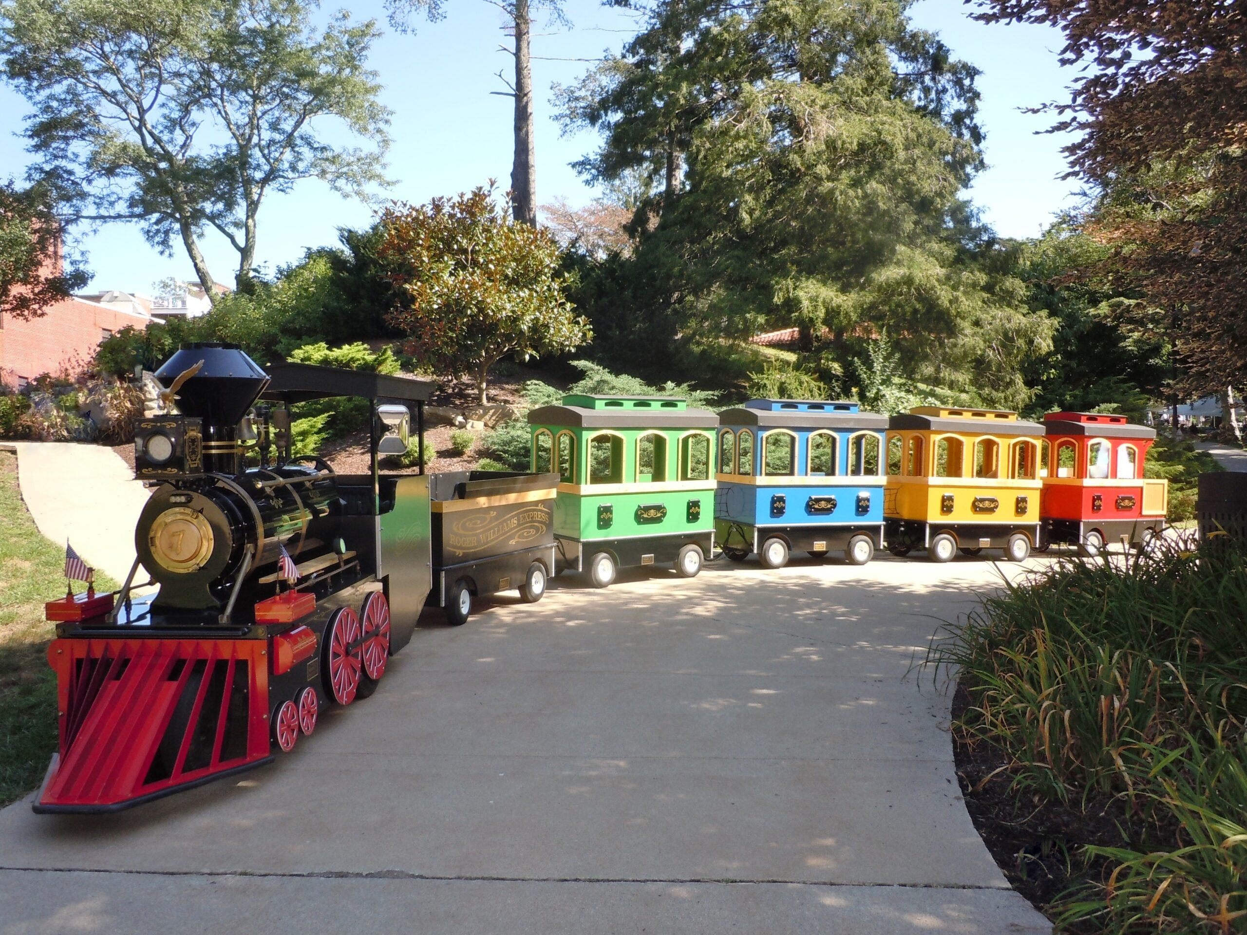 A colorful miniature train with multiple carriages on a path.
